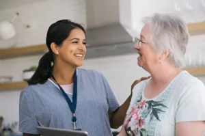 A healthcare professional smiling and interacting with a senior patient at home – illustrating compassionate care and the concept of what PPL means in healthcare.